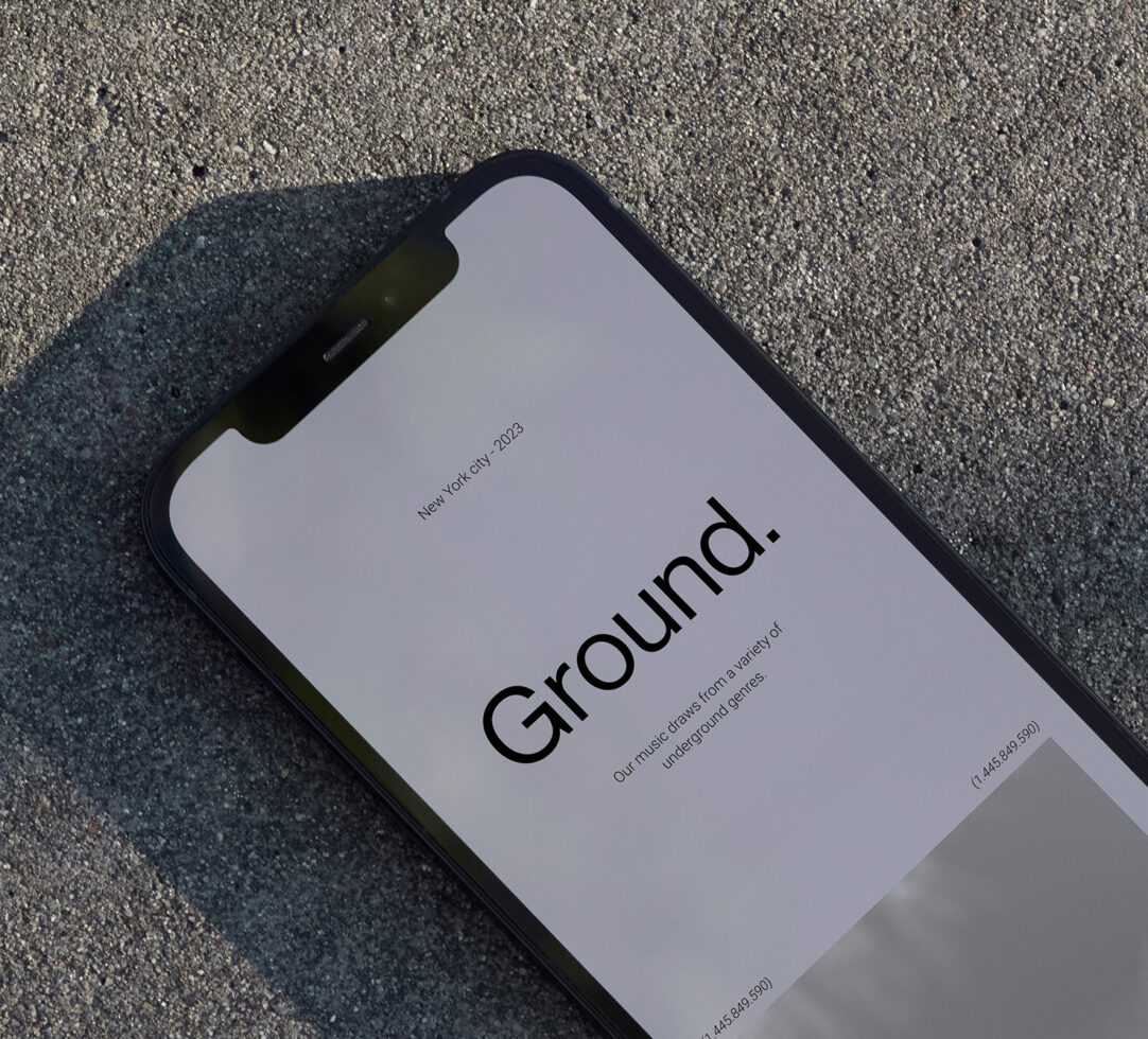 Black iPhone on concrete showing minimal app screen with "Ground" branding text