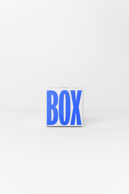 Single white cube box with large blue sans serif letters centered on clean white surface