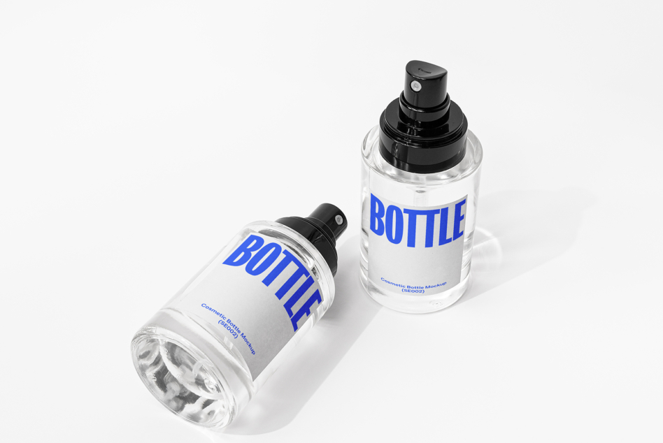 Two clear spray bottles with black pump tops, white label with blue BOTTLE text