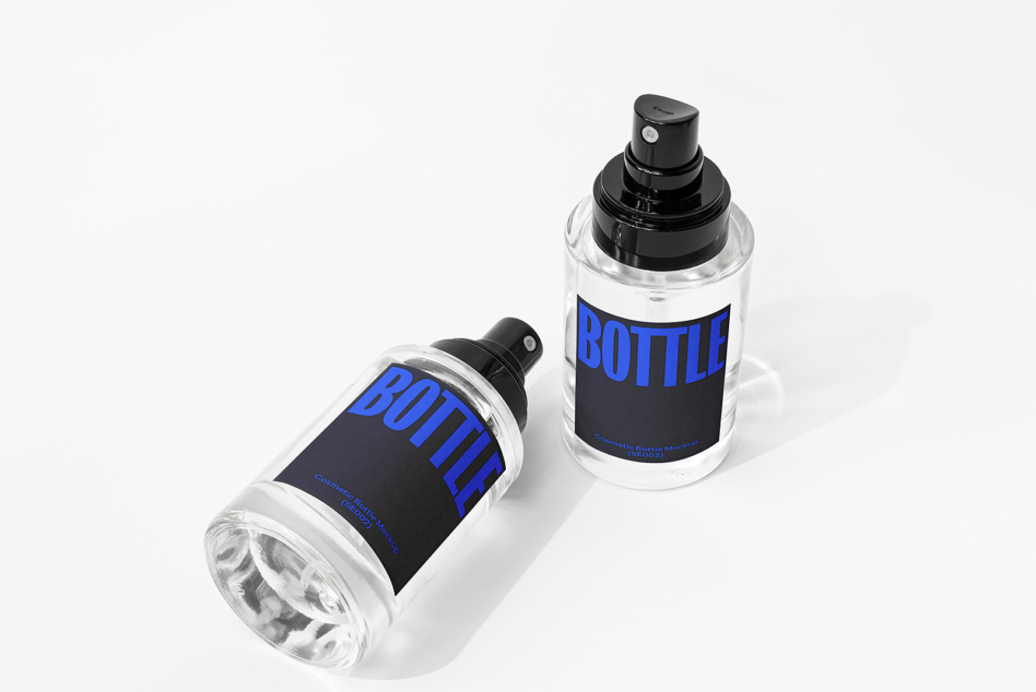 Two clear spray bottles with black pump tops, dark label with blue BOTTLE text