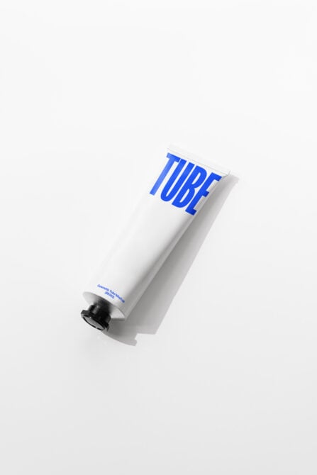 Single white cosmetic tube with vibrant blue letters on diagonal angle overhead view