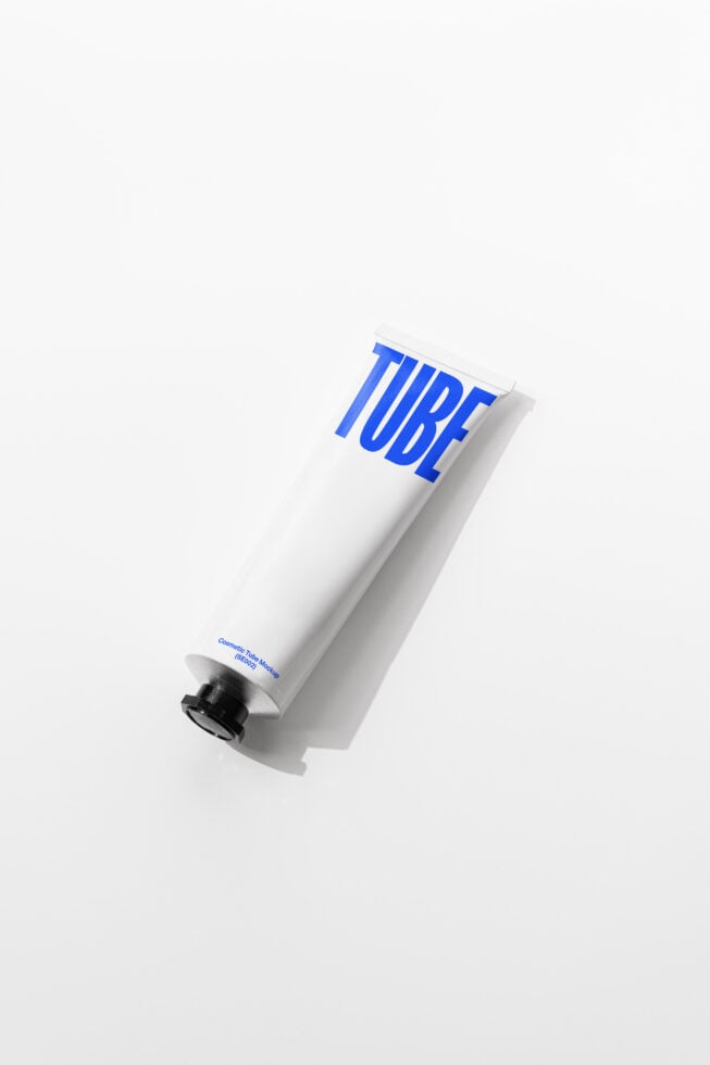 Single white cosmetic tube with vibrant blue letters on diagonal angle overhead view