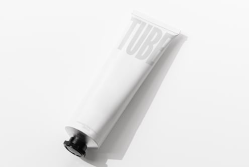 White cosmetic tube with debossed TUBE text on clean minimal background tilt
