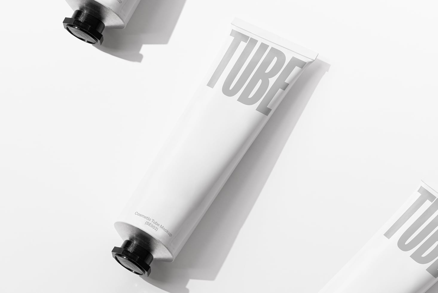 White cosmetic tube with black cap on angled surface showing embossed TUBE text