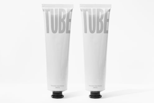 Two white cosmetic tubes with embossed TUBE lettering on plain packaging