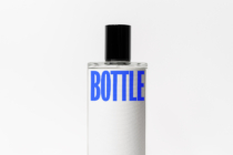 Clear cosmetic bottle with black cap, blue BOTTLE text on white label design