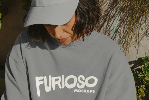 Person wearing blue-gray crewneck sweatshirt with cream Furioso logo, white cap visible