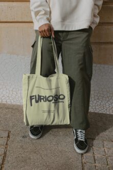 Cream colored tote bag carrying design with dark Furioso Mockups branding typography