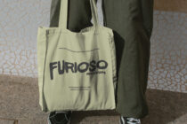 Pale yellow tote with dark Furioso Mockups lettering sitting against wall backdrop