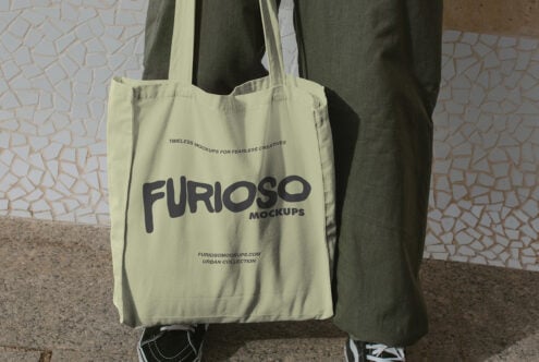 Pale yellow tote with dark Furioso Mockups lettering sitting against wall backdrop