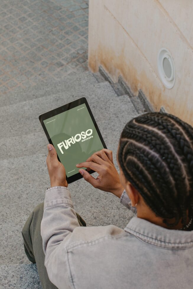 Person holding tablet with green screen looking down at ground