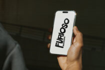 Hand holding white iPhone with black Furioso Mockups vertical logo text