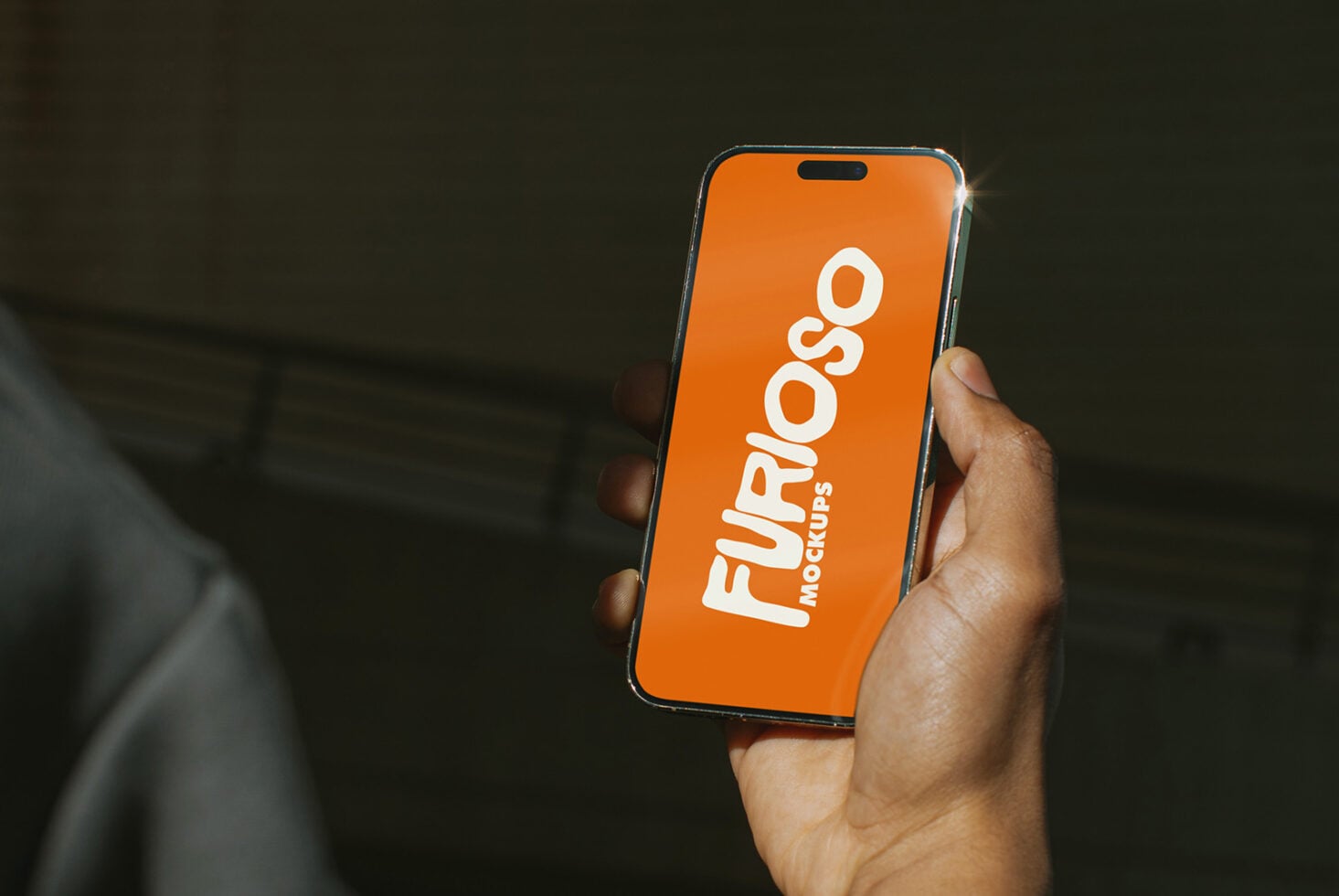 Orange iPhone in hand showing white Furioso Mockups logo on bright display