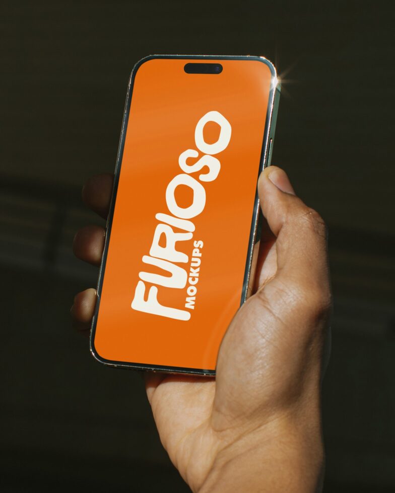 Hand holding orange iPhone displaying white Furioso Mockups branding on screen