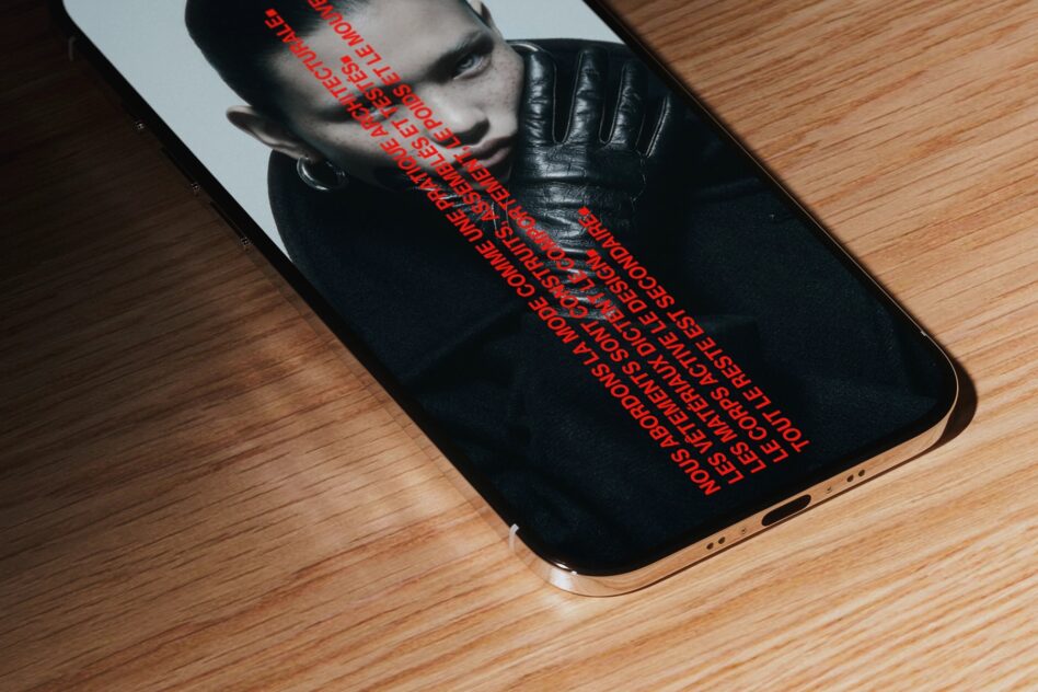 iPhone mockup with red diagonal text overlay on black screen, sitting on wood table