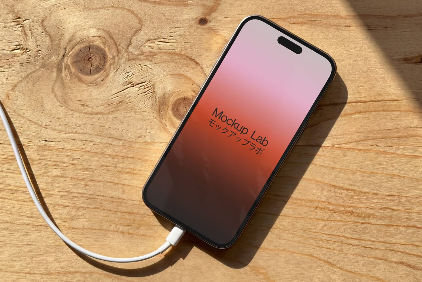 iPhone with pink to red gradient screen on wood surface showing Mockup Lab