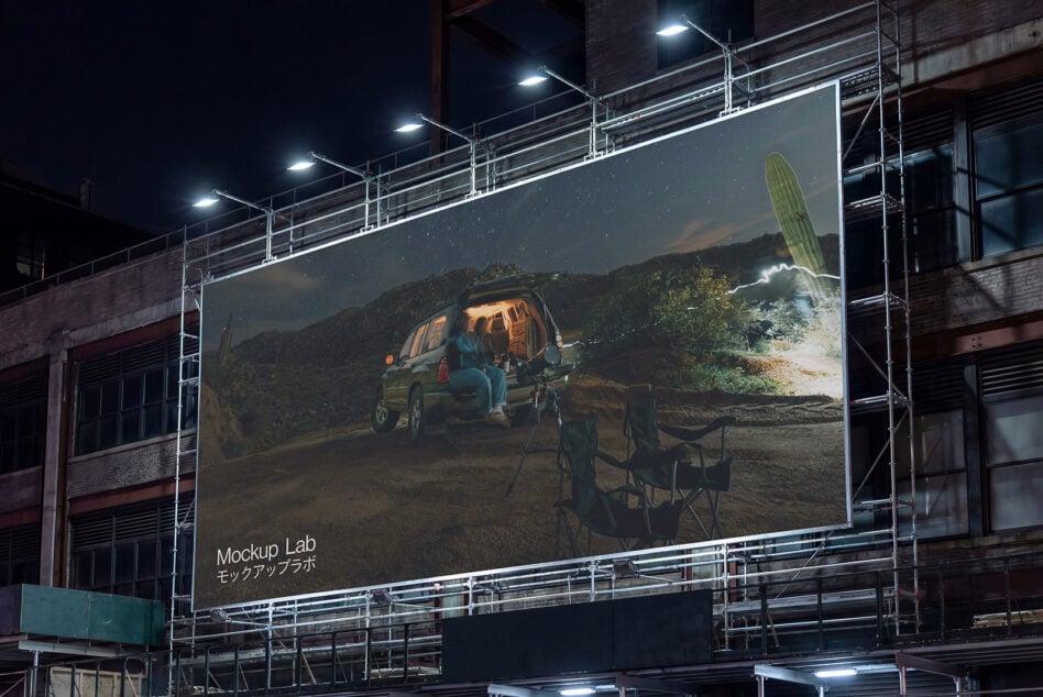 Large night billboard showing camping scene with van in mountains