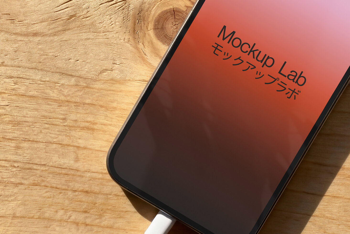 iPhone on wood surface showing coral gradient screen with Mockup Lab logo