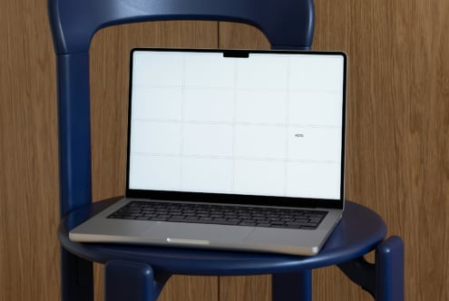 MacBook on navy chair with white grid screen close up shot
