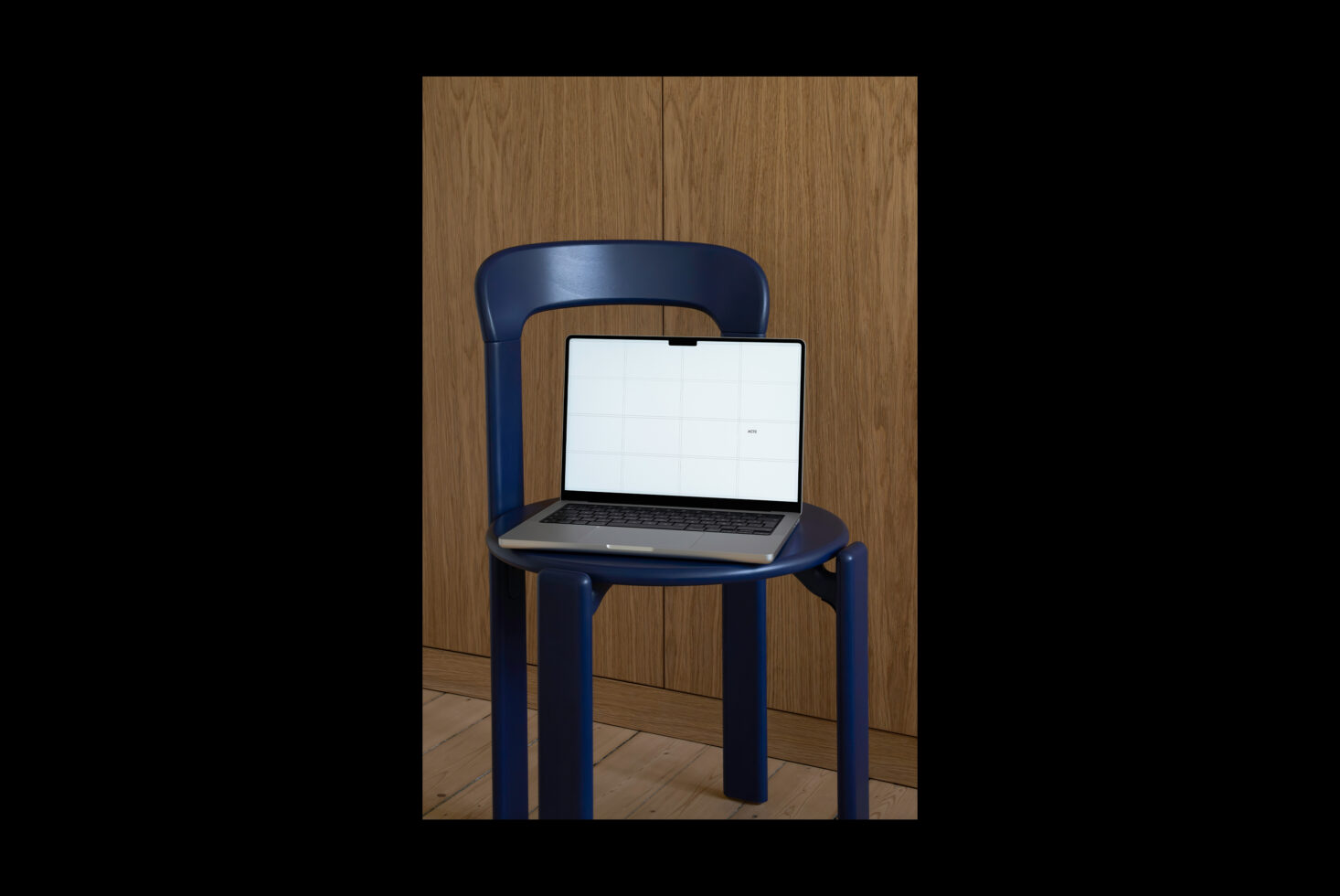 MacBook on navy blue modern chair against wood wall background
