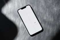 Black phone with white screen showing grid layout on gray fabric