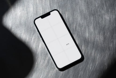 Black phone with white screen showing grid layout on gray fabric