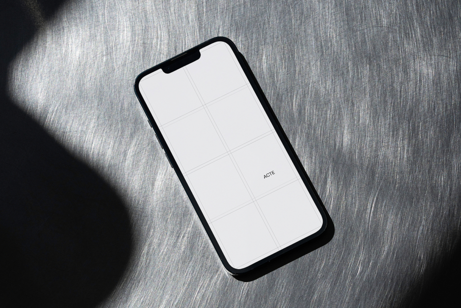 Black phone with white screen showing grid layout on gray fabric