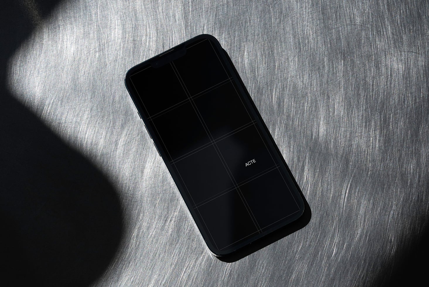 Black phone with dark screen displaying grid on textured gray surface