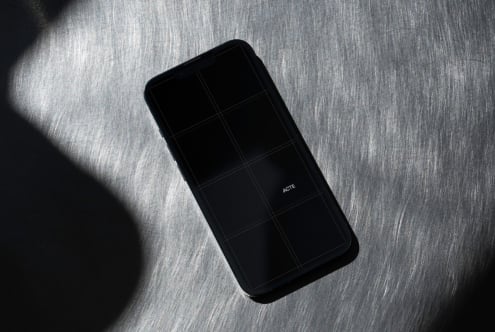 Black phone with dark screen displaying grid on textured gray surface