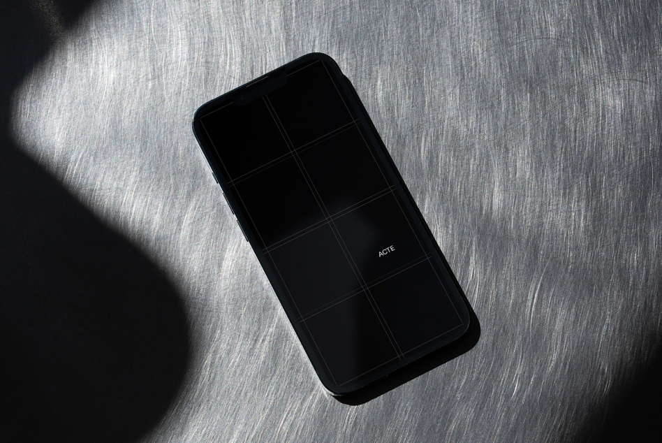 Black phone with dark screen displaying grid on textured gray surface
