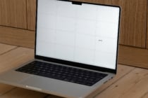 Silver laptop with white screen showing grid layout on wooden desk
