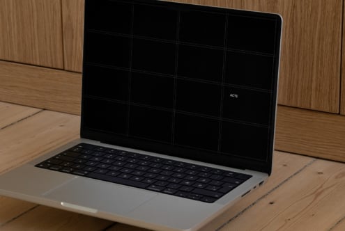 Silver laptop with black screen showing grid layout on wooden desk