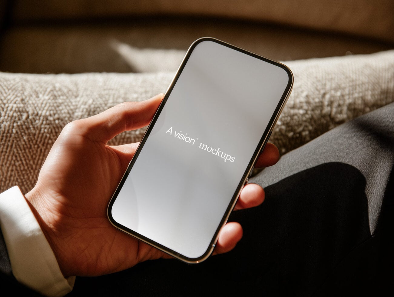 Hand holding phone with blank gray screen on beige fabric couch