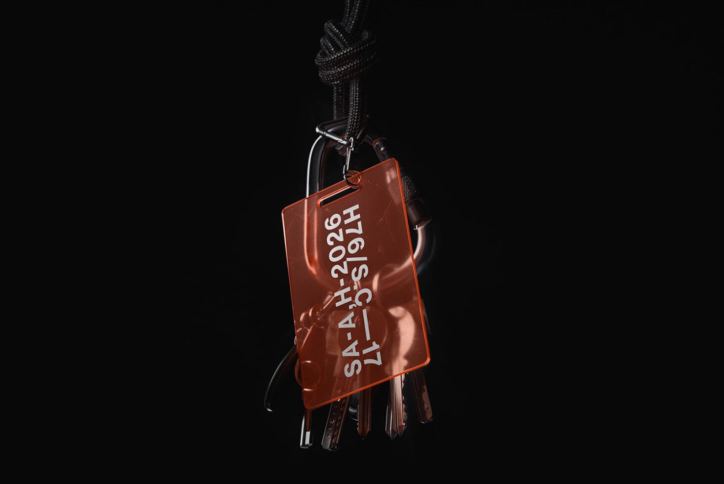 Rust acrylic keychain with embossed text hanging from braided cord