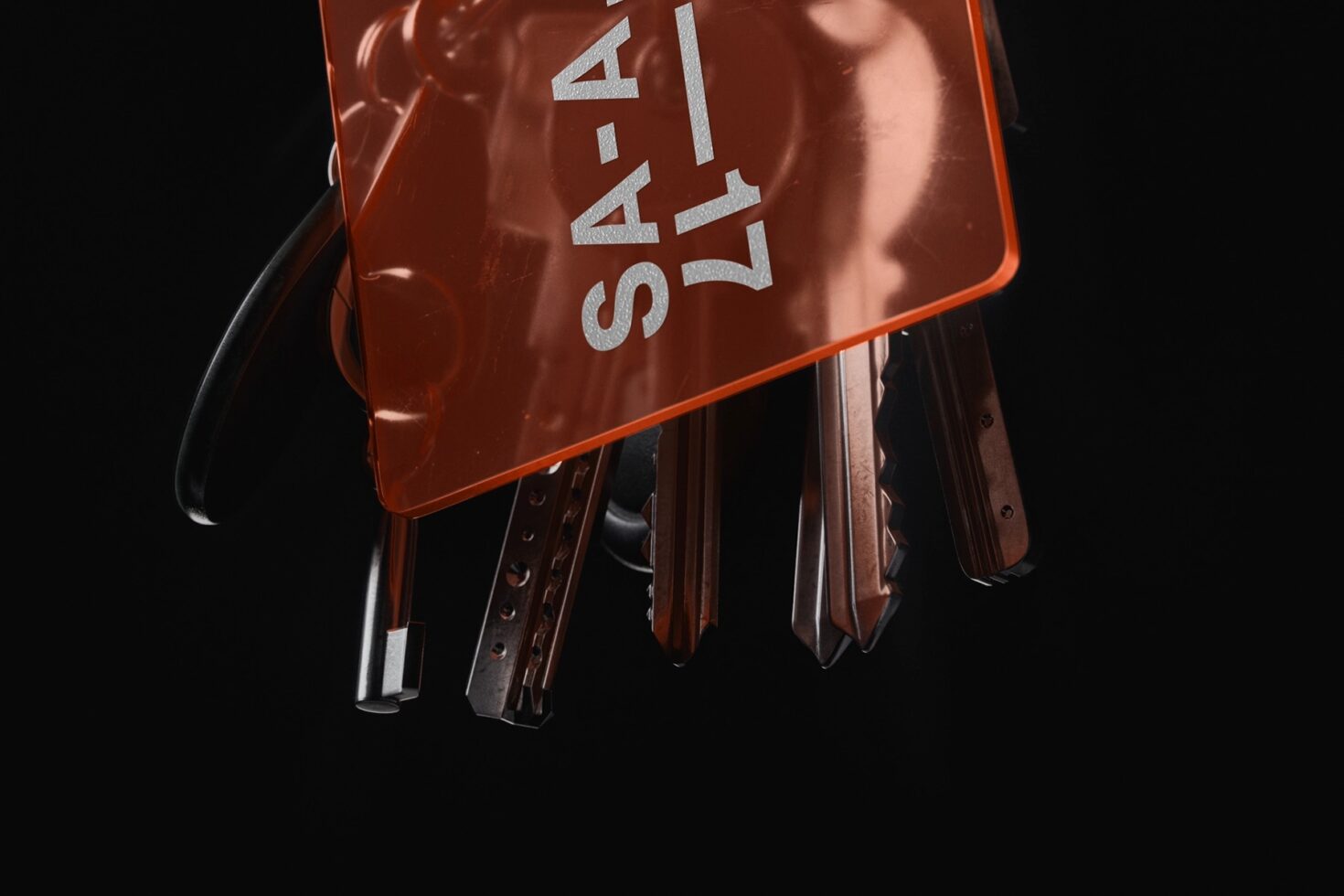 Red metallic keychain holder with hanging keys on black background