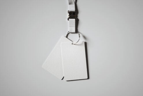 White lanyard with black clip holding blank white ID badge card