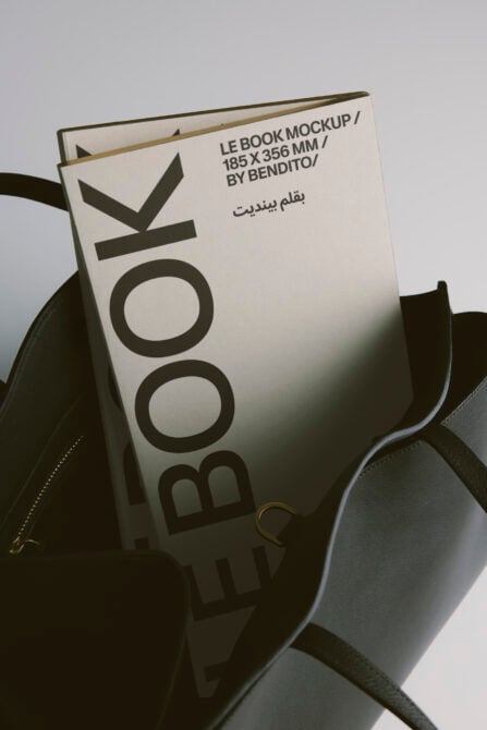 Cream book cover propped in black leather bag, soft product shot styling