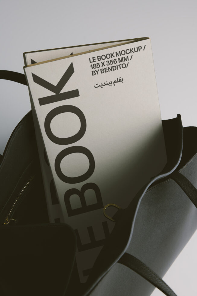 Cream book cover propped in black leather bag, soft product shot styling