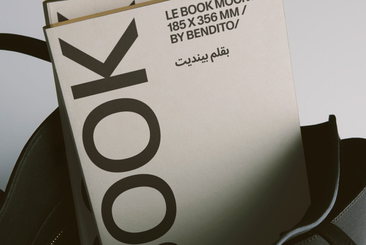 Beige book cover in black bag with shadow detail, flat minimalist styling