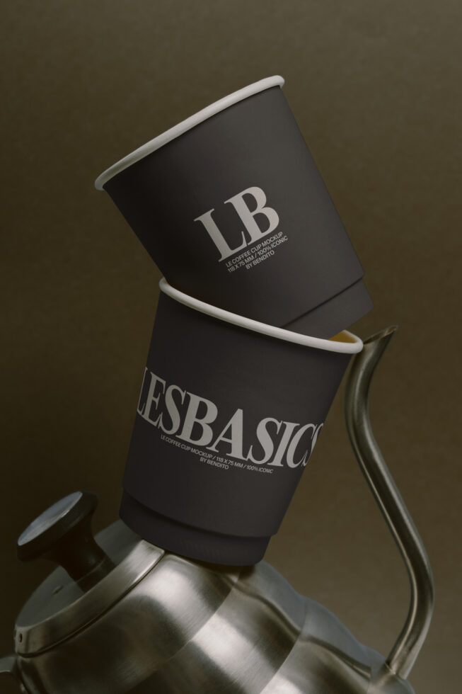 Stacked black coffee cups with white rim on metal holder against neutral background