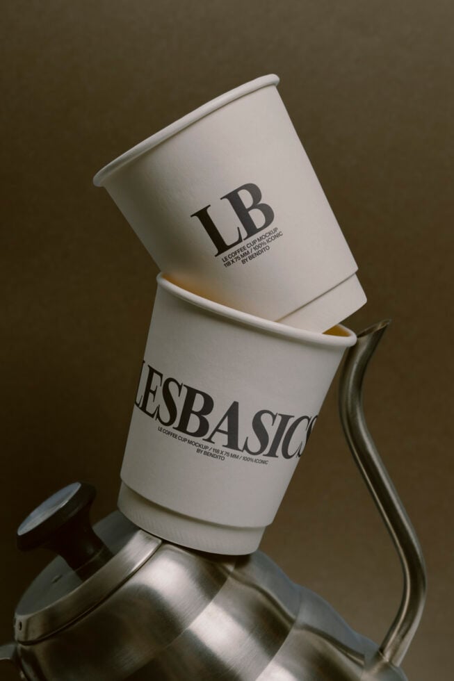 Stacked white coffee cups with white rim balanced on curved metal handle