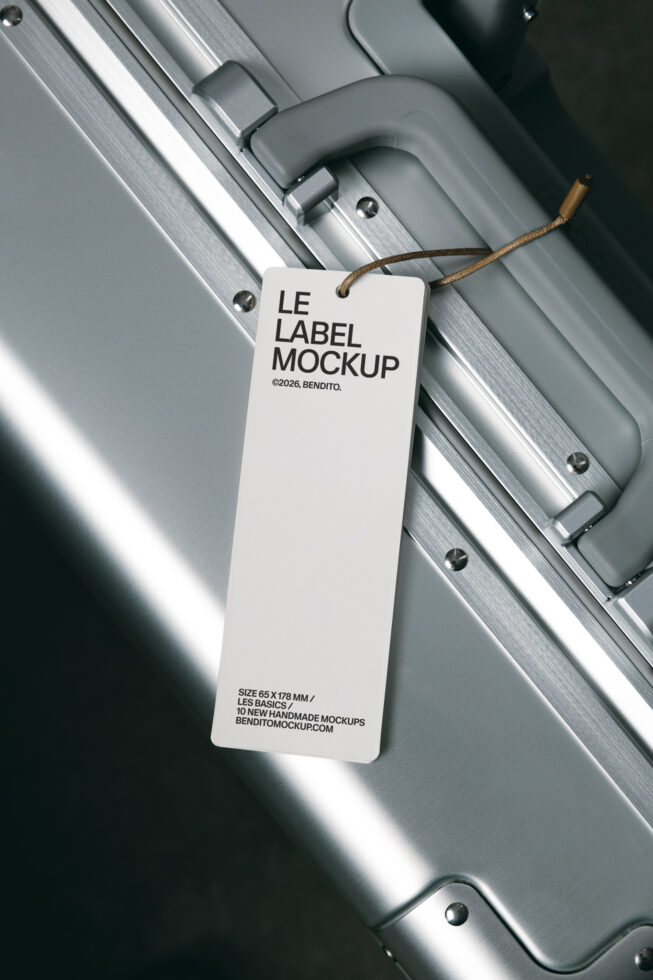 White hang tag label mockup attached to brushed aluminum luggage with rope detail