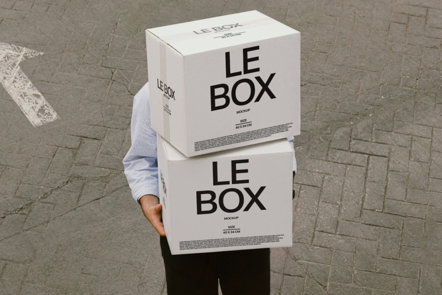 Person holding stacked white cardboard boxes labeled LE BOX on pavement