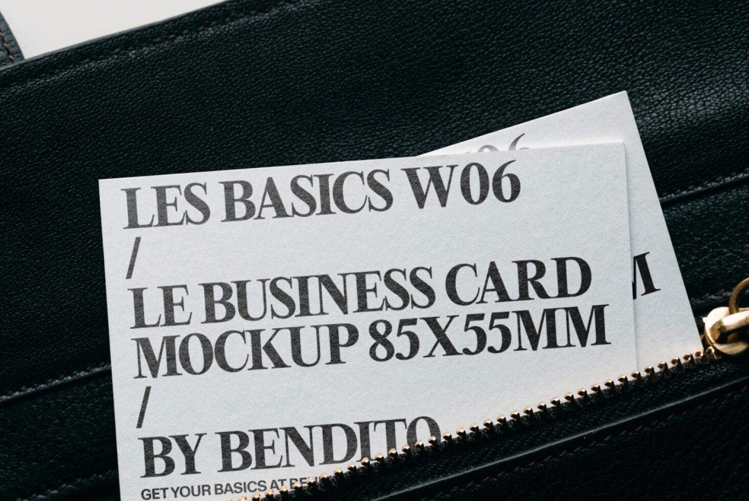 White business card mockup peeking from black leather bag with gold zipper
