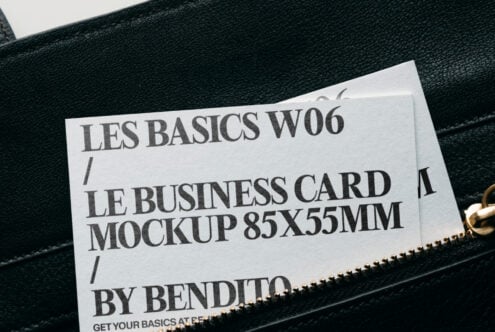 White business card mockup peeking from black leather bag with gold zipper