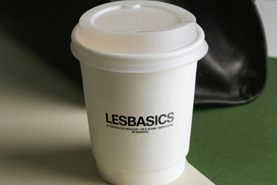 White paper coffee cup with lid showing LESBASICS branding text mockup