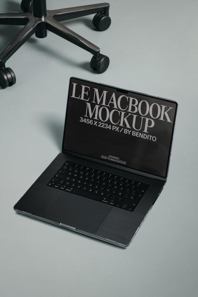 MacBook mockup on desk with dark screen next to office chair