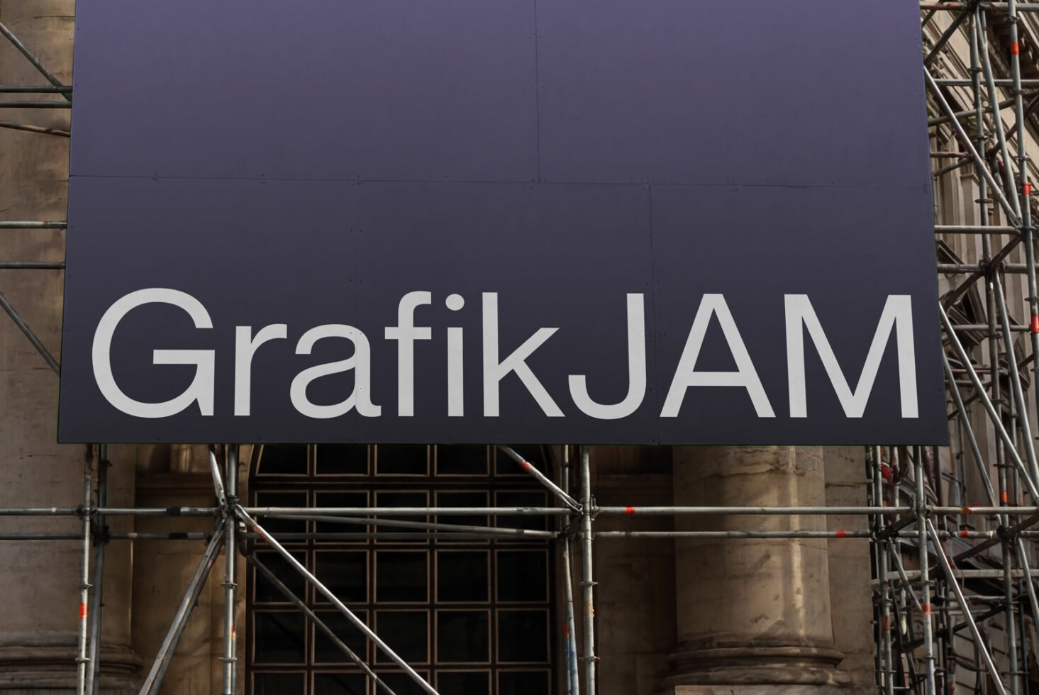 Navy blue construction billboard with white GrafikJAM text on facade