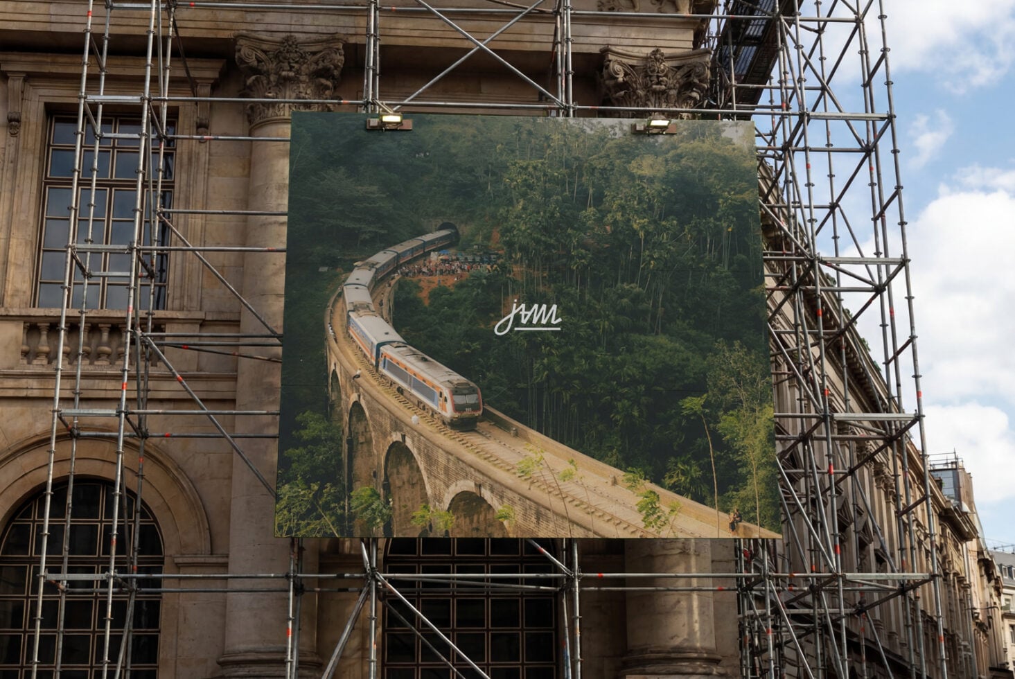 Large outdoor billboard showing train on viaduct with scaffolding around building