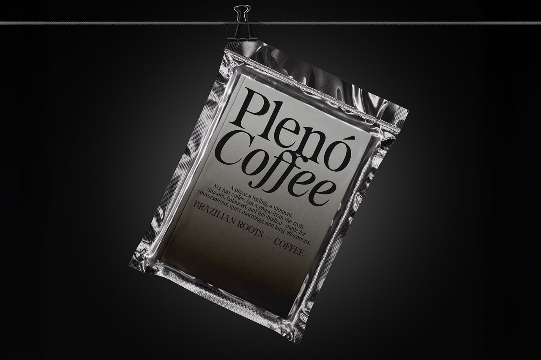 Silver coffee packet hanging on clip against dark background mockup